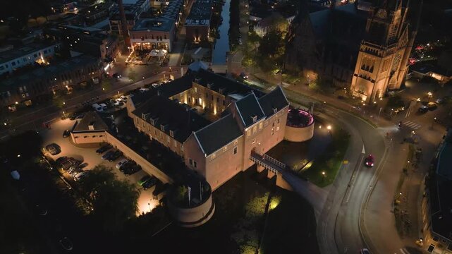 Cinematic drone shot of a historic European city at night with glowing street lights and illuminated buildings (woerden)