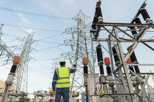 Engineer uses a thermal camera to inspect high voltage switchyard equipment in a power substation, supporting preventive maintenance, safety checks, and grid reliability.