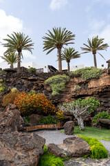 Fototapeta premium A stunning view of Jameos del Agua on Lanzarote, showcasing palm trees, lush greenery, and unique rock formations, perfect for a relaxing getaway.