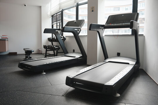 Two modern treadmills placed in a clean indoor gym with large windows and natural lighting