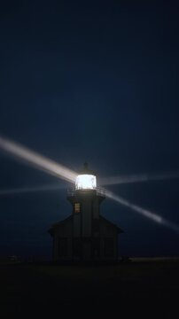 Vertical Screen: Lighthouse beacon glowing in foggy night sky with strong light rays cutting through mist near Mendocino, California, USA forming cinematic coastal night scene