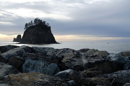 Big Rocks on Beach looking out to an Island with pine trees