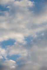 Fototapeta premium Cloudy sky with fluffy white and gray cumulus clouds. Vertical heaven background