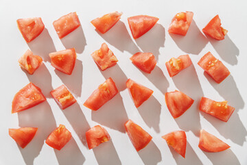 Rows of red tomato chunks on white background. Top view