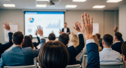 Fototapeta premium Audience raising hands in a business seminar with charts on projector screen