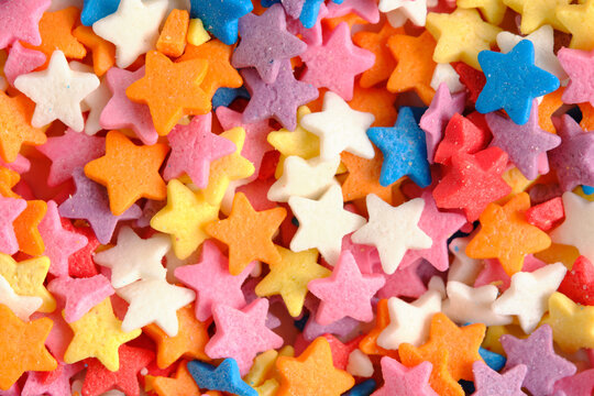 Extreme close up sugar stars in pastel and bright colors, showing fine details sweet confectionery texture.