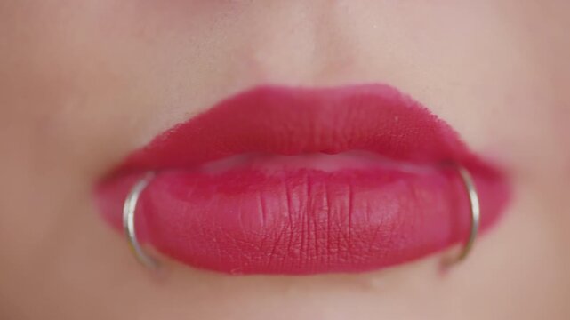 Woman's lips with snake bites piercing and pink lipstick