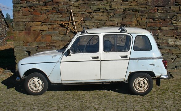 Old Renault 4 car parking near stone wall