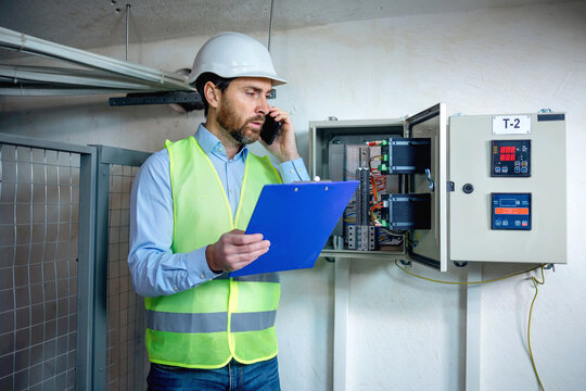 Electrical Plant Engineer in charge of monitoring and maintaining the factory power supply work system have a call holding clipboard, detected a problem