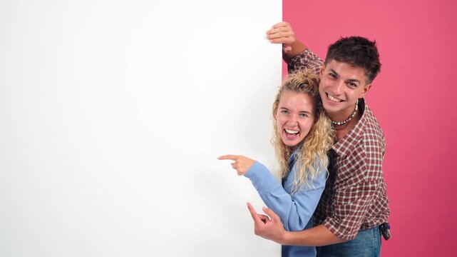 A pair of enthusiastic friends playfully showcasing an empty canvas while smiling and enjoying their time together, making it perfect for themes of collaboration and creativity in various projects.