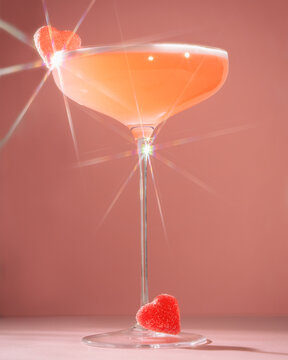 pink cocktail in a glass with love heart sweets on the side
