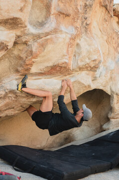 Climber finds foothold on overhang in Joshua Tree boulder
