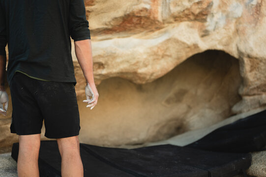 Climber with chalked hands prepares to climb boulder with copy space