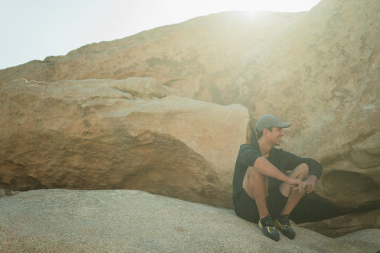 Smiling climber resting on boulder in sunlight with copy space