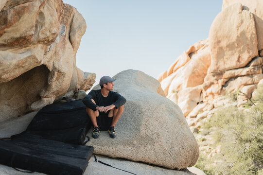 Diverse climber resting on boulder enjoying Joshua Tree scenic view