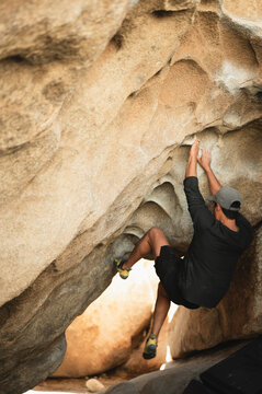 Climber tackling difficult overhang boulder in Joshua Tree