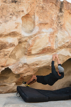 Climber bouldering on sandstone rock in Joshua Tree desert