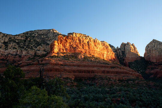 Golden hour light illuminating red rock cliffs in desert landscape