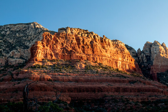 Sunlit red rock formation glowing at golden hour in desert terrain
