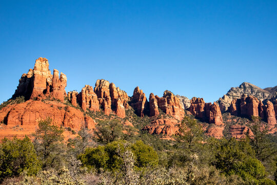 Red rock spires and cliffs rising above lush desert vegetation