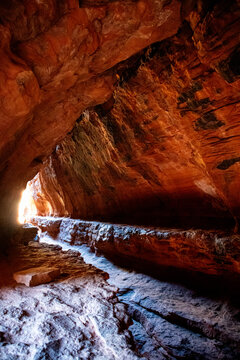 Sunlight entering red rock cave with textured sandstone walls