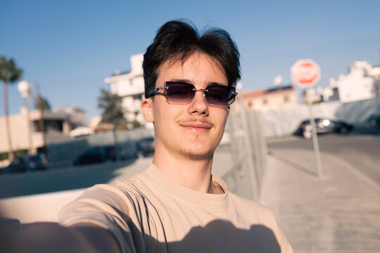 Confident young man taking selfie wearing sunglasses