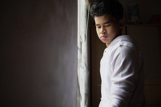 Young Asian man opening or closing window blinds at home, looking out for hope or privacy, morning routine or mental health concept