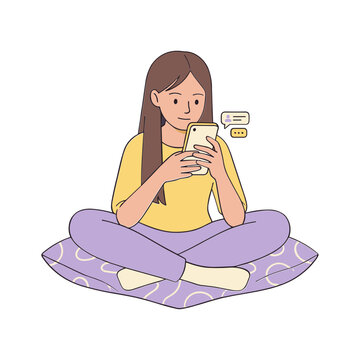 A woman sits cross-legged on a mat, engrossed in her phone.