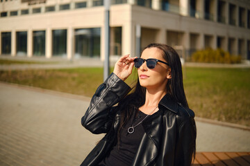 Fototapeta premium Woman in sunglasses enjoying sunny day outdoors near building