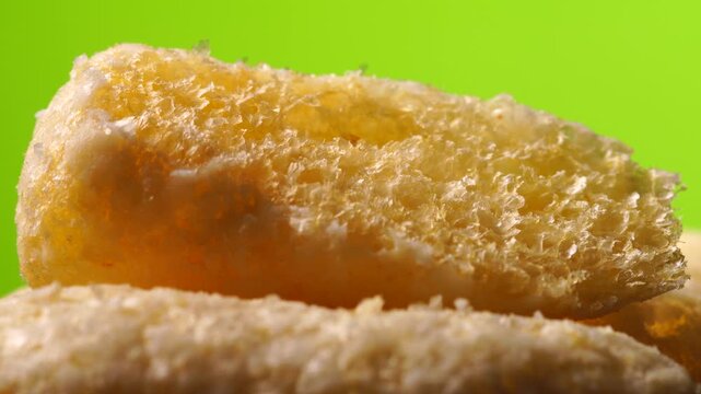 Detailed texture of a corn snack puff, close-up rotation, on a green background.