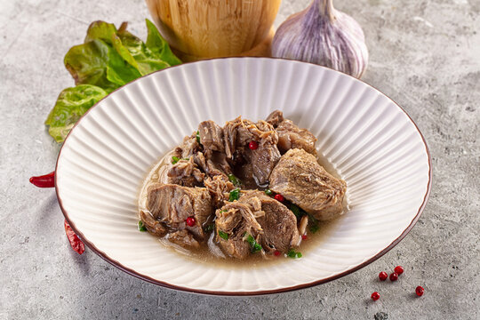 Braised meat stew with peppercorns and green onions in a white bowl