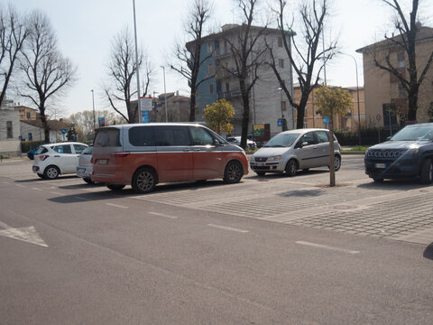 Modern VW Multivan T7 two tone orange and silver parked in concrete lot beside urban buildings under a sunny blue sky