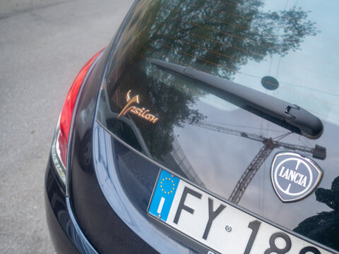 Lancia Ypsilon rear with brand logo, Ypsilon nameplate, and European license plate displaying reflections on the dark paint