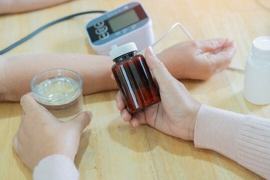 Female caregiver with bottle of pills and glass of water while sitting at table