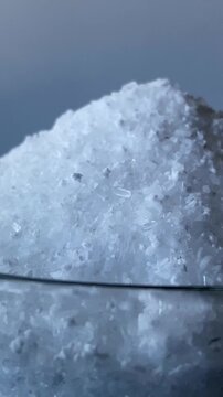 A mountain of salt. Salt. A glass of water. Epsom salts. Slow motion video. . High quality 4k footage
