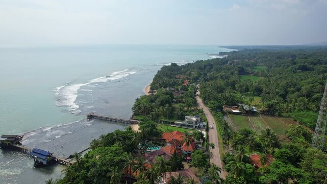 Aerial drone footage of the western coastline of Java island, in Cinangka area, Serang regency, Banten, Indonesia, with blue waters, villas and reef