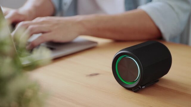 Smart Speaker Virtual Assistant or Artificial Intelligence Concept by Man Typing Laptop Computer with Smart Speaker
