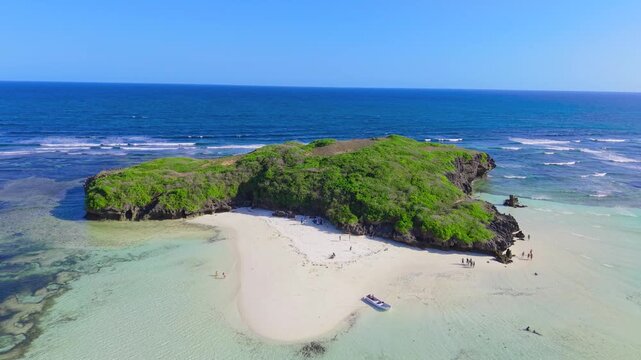 Aerial view of a small green island featuring a white sand beach and people near turquoise ocean water at Watamu Beach, Kenya.