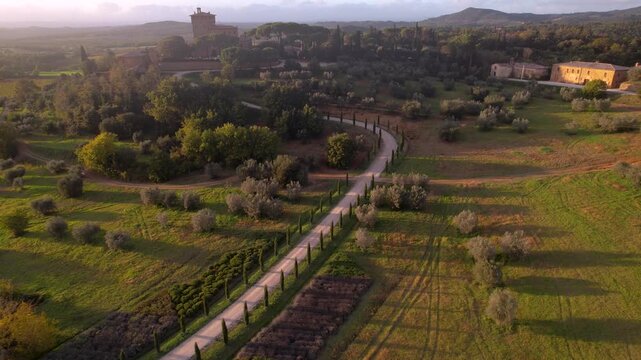 Cinematic Aerial 4k View of Val d'Orcia at Sunset. Winding Road with Cypress Trees and Traditional Tuscan Farmhouse in Misty Golden Light. Scenic Landscape Tuscany Italy.