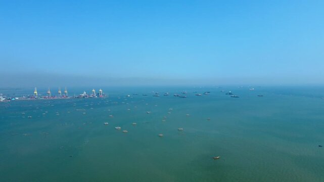 Aerial view of a bustling port with numerous ships dotting the tranquil turquoise waters under a clear sky, Semarang, Indonesia.