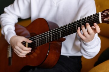 Fototapeta premium Close Up of Musician Hands Playing Classical Acoustic Guitar, Guitarist Fingers Holding a Chord on the Fretboard, Musical Education and Practice Concept, Creative Hobby and Talent.