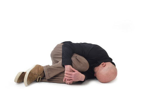    man lying on the ground in the fetal position on white background