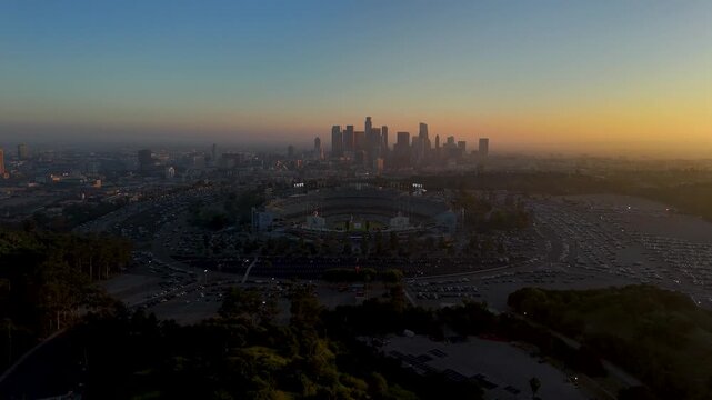 Los Angeles, United States - 25 March 2026: Aerial view of Dodger Stadium with the city skyline, bathed in the warm glow of sunrise, creating a stunning contrast.