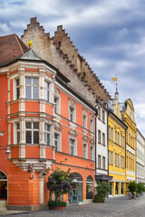 Fototapeta premium Historical red building with corner bay window in Straubing, Germany. Old town houses in pedestrian street under cloudy sky
