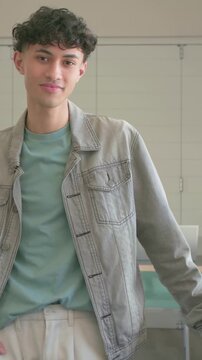 Vertical video: Standing man shifting, smiling in classroom, camera recording, lavalier on jacket