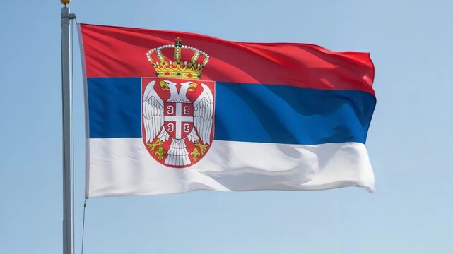 Serbian flag waving in the wind against a clear blue sky  