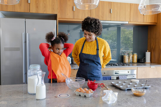 African American mother and daughter stirring batter at kitchen counter, with glass mixing bowl