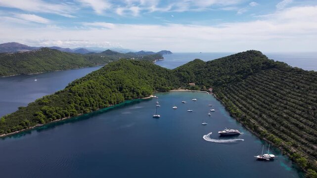 Aerial view of islands covered in lush green trees with the crystal clear blue sea dotted with boats and yachts, Elaphiti islands, Dalmatian Coast, Dubrovnik-Neretva County, Croatia.