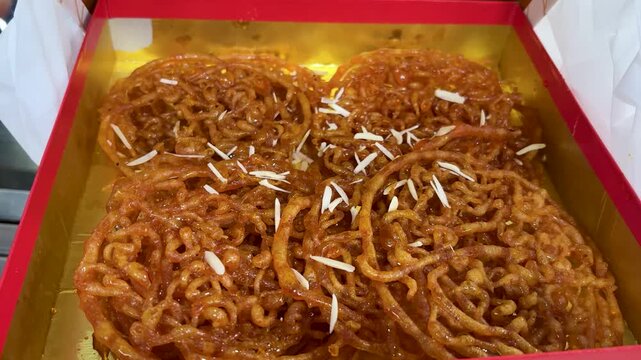 fresh jalebi sweets in box with syrup and dry fruits topping
