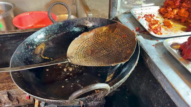 spicy fried chicken pieces being lifted from hot oil in kadhai indian street food cooking close up